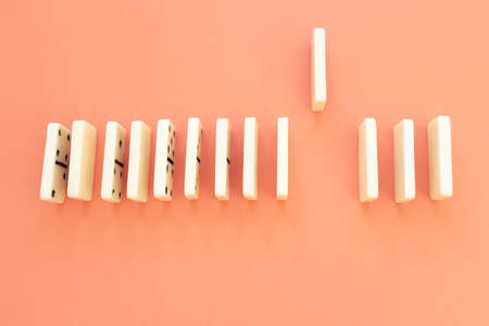 A piece of dominoes is up while the rest are lined up to make a domino effect, avoiding the spread of the effect.の写真素材