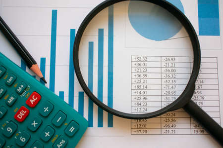 A calculator, a pencil and a magnifying glass over a paper full of charts and graphics. Economy and business conceptsの写真素材