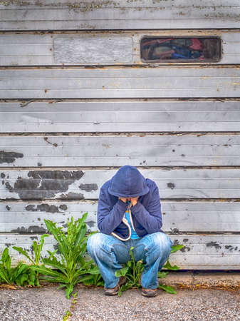 woman dress in blue crouched against a garage doorの写真素材