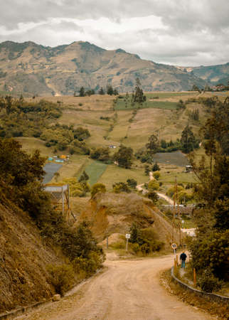 Beautiful rural scene in the Andes mountains of Choconta, Cundinamarca, Colombia. An earth road, a man walking, crops and a cloudy sky can be seen on this panorama.の写真素材