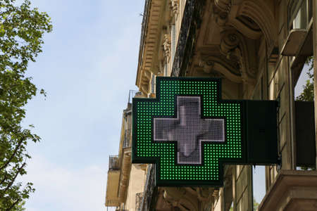 French pharmacy sign (drugstore symbol): green cross on a parisian facade giving time.の写真素材