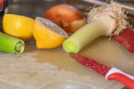 Chopped onion for seasoning on a white board, with zucchini, orange and fresh celery.