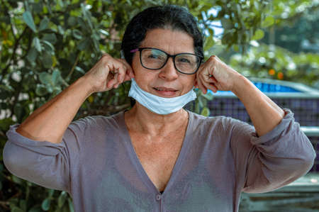 A nice and beautiful lady with a surgical mask looking at the camera, protected against the Covid 19...