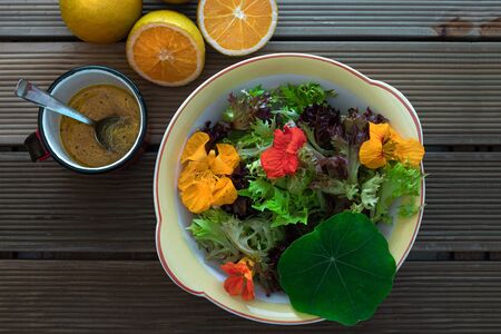 A beautiful and refreshing green salad with leaves and edible flowers. Accompanies a tasty orange sauce.の写真素材