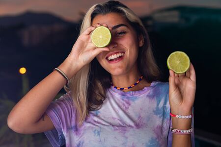 An image of a beautiful amazing happy young woman posing on a dark background, holding lemons and...