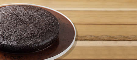 Dark vegan chocolate cake, wooden background. Space for text.