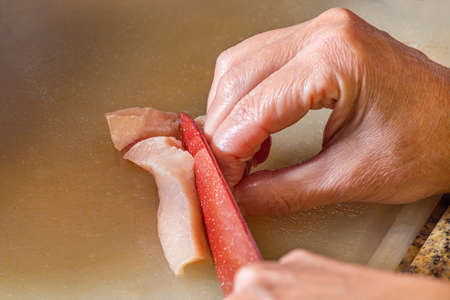 Slicing pieces of diced chicken breast.