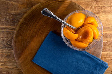 Fresh peaches in syrup in the bowl on wooden background.の写真素材