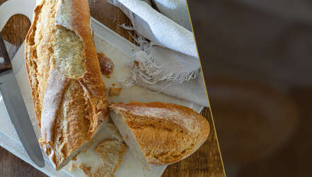 A fresh and crispy Italian bread, on a white cutting board and wheat flour. Selective focus. Space...