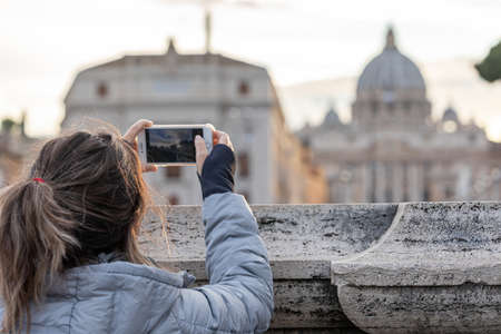 Piazza San Pietro, Vatican, Italy - July 03, 2019: Woman taking picture of St. Peter's Basilica in front of the Vatican.のeditorial素材