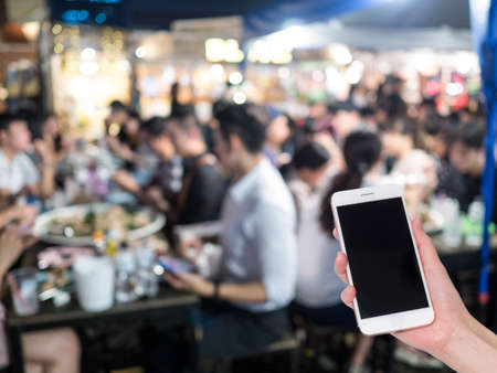 Hand holding mobile phone with Shopping mall or department store blurred background and bokeh light. Social network, internet conceptの写真素材