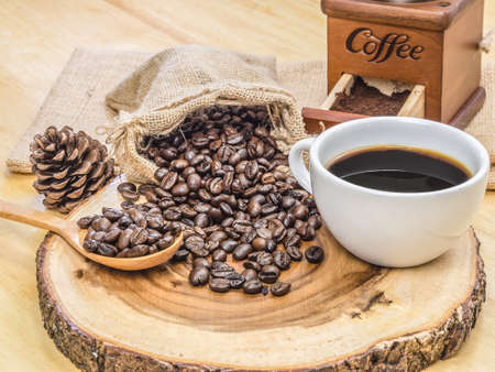 White coffee cup on top wooden table with blank price list board, coffee grinder and coffee beanの写真素材