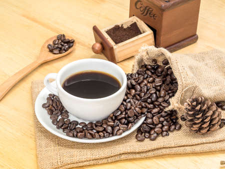 White coffee cup on top wooden table with blank price list board, coffee grinder and coffee beanの写真素材