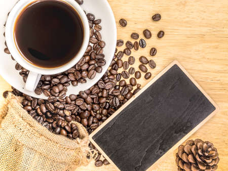 White coffee cup on top wooden table with blank price list board, coffee grinder and coffee beanの写真素材