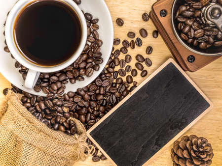 White coffee cup on top wooden table with blank price list board, coffee grinder and coffee beanの写真素材
