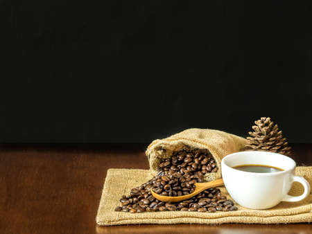 White cup coffee with coffee beans and blank chalk board on wooden top tableの写真素材