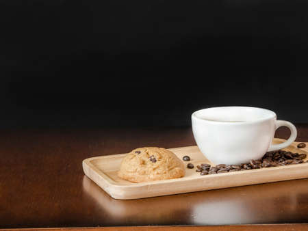 White cup coffee with coffee beans and blank chalk board on wooden top tableの写真素材