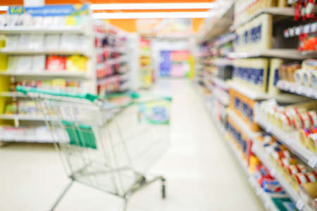 Supermarket aisle with empty shopping cart blurred backgroundの写真素材