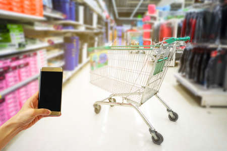 Hand holding mobile phone with shopping mall blurred background and bokeh light, Internet, Social...