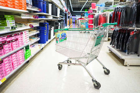 Supermarket aisle with empty shopping cart blurred backgroundの写真素材