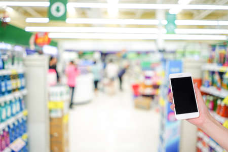 Hand holding mobile phone with shopping mall blurred background and bokeh light, Internet, Social medaiの写真素材
