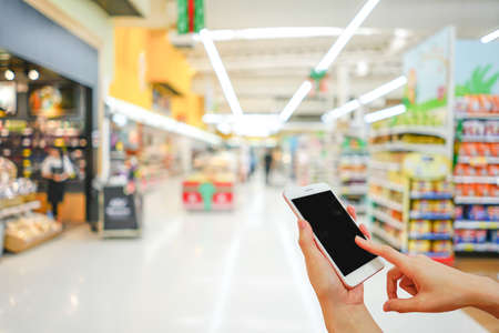 Hand holding mobile phone with shopping mall blurred background and bokeh light, Internet, Social medaiの写真素材