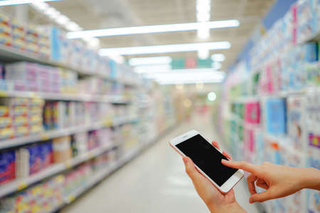 Hand holding mobile phone with shopping mall blurred background and bokeh light, Internet, Social medaiの写真素材