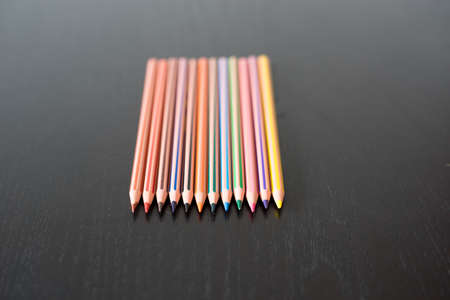 Straight in line colored pencils on black wooden tableの写真素材