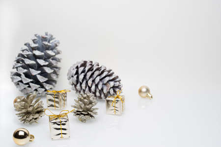 Gold christmas gift boxes with cones and golden christmas bulbs on white backgroundの写真素材