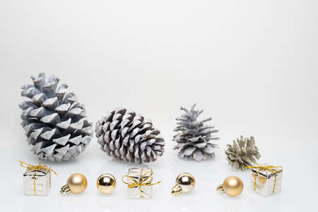 Gold christmas gift boxes with cones and golden christmas bulbs on white backgroundの写真素材