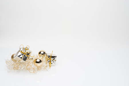 Silver christmas gift boxes with golden christmas bulbs in the bottom left corner on white backgroundの写真素材