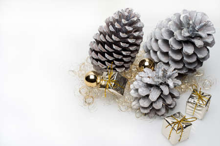 Gold christmas gift boxes with cones and golden christmas bulbs in the right corner on white backgroundの写真素材