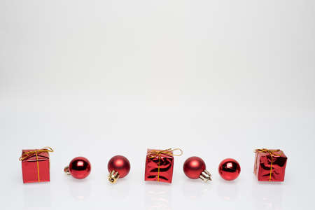 Red christmas gift boxes with red christmas bulbs in the bottom third on white backgroundの写真素材