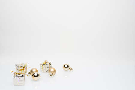 Silver christmas gift boxes with golden christmas bulbs in the bottom left corner on white backgroundの写真素材