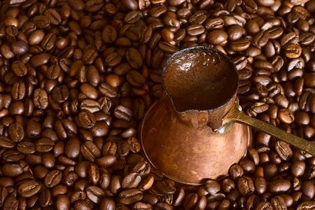 Fresh-made Turkish coffee in coffee-pot with long handle on scattered coffee-beansの写真素材