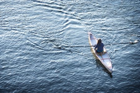 Young woman in a row boat surrounded by waterの写真素材