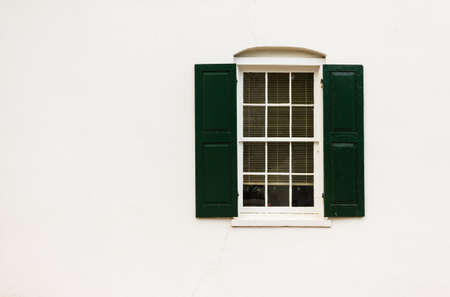 White window on brick wall with green shuttersの写真素材