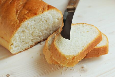 Slices of bread and knife on a wooden table