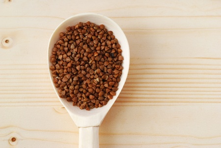 Buckwheat in the wooden spoon on the tableの写真素材