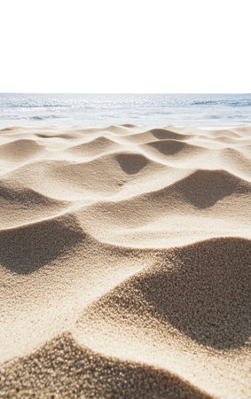 Close-up of textured beach sand formations with natural ripples and shadows in foreground and calm blue ocean, isolated on a white backgroundの素材