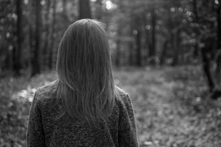 A young girl walks alone in a cold misty forest.の写真素材
