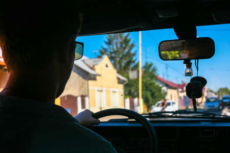 Young guy driving an old retro car. Back view.