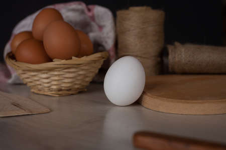 eggs in a basket on a wooden table with a rolling pinの写真素材