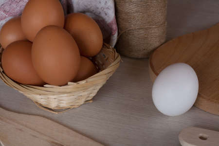 Eggs in a basket on a wooden table with a kitchen towelの写真素材