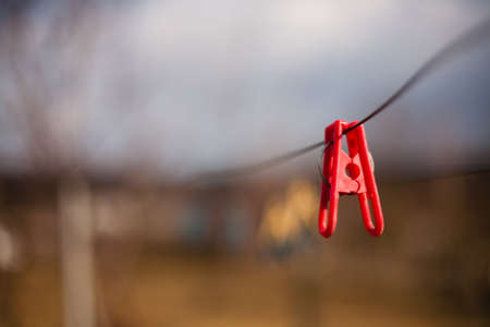 Red plastic clothespins on a clothesline against a blurred background.の写真素材