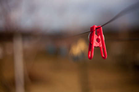 Red plastic clothespins on a clothesline on a blurred background.の写真素材
