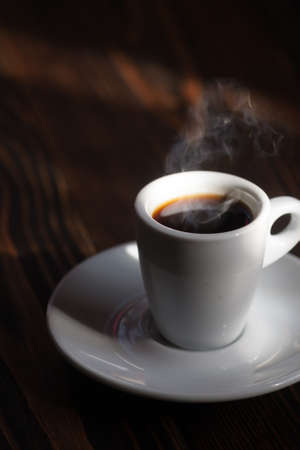 Cup of coffee with steam on a wooden table, selective focusの写真素材