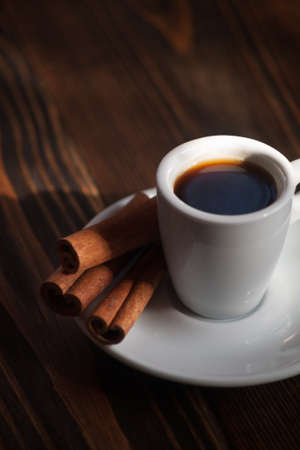 Cup of coffee with cinnamon sticks on a wooden table, selective focusの写真素材