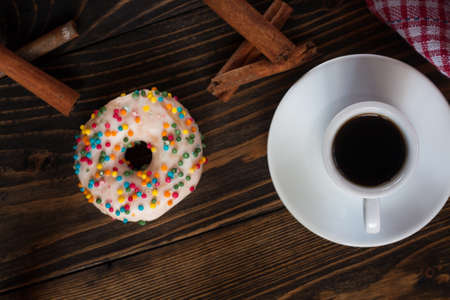 Donut with a cup of coffee on a wooden background, top viewの写真素材