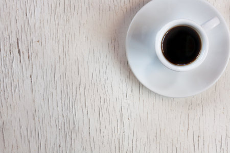 Cup of coffee on wooden table, top view. Space for text